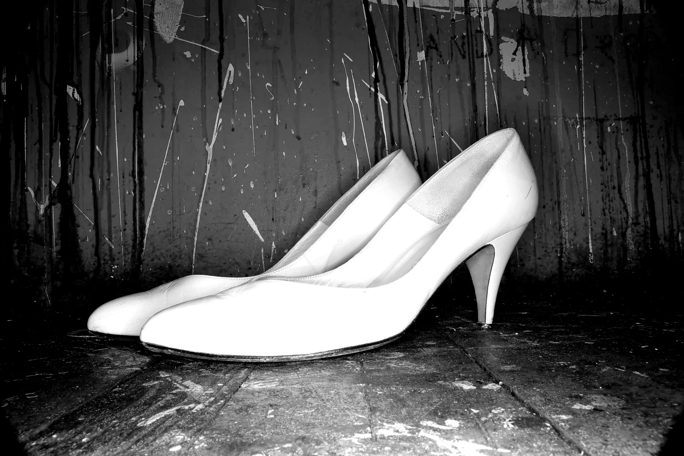 White high heels leaning against a dark wall