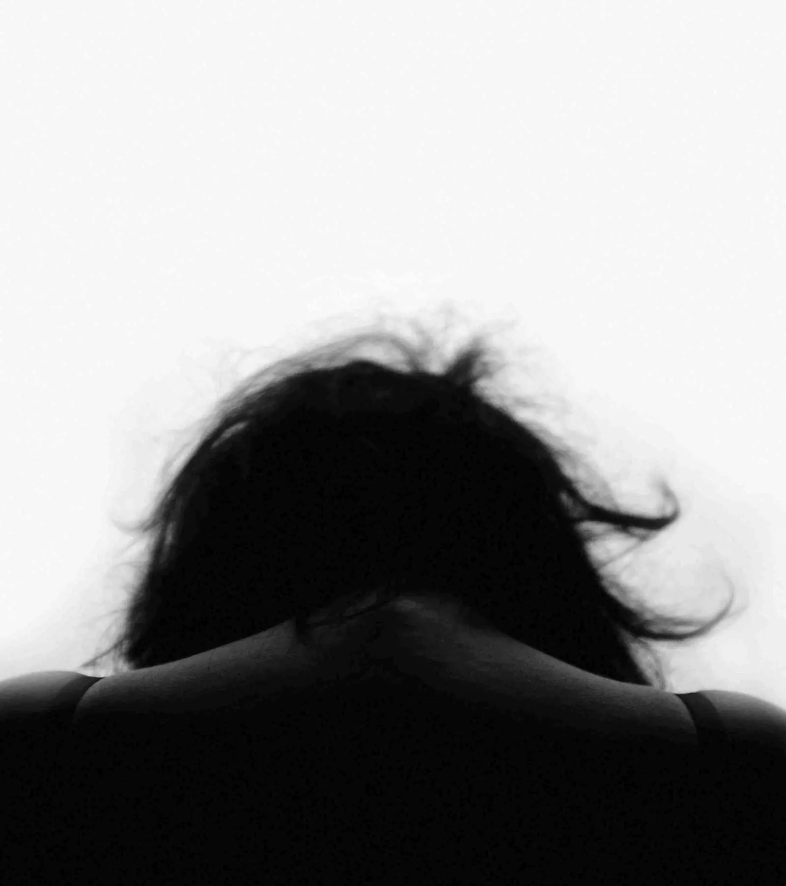 A woman seen from behind, hair lifted by wind