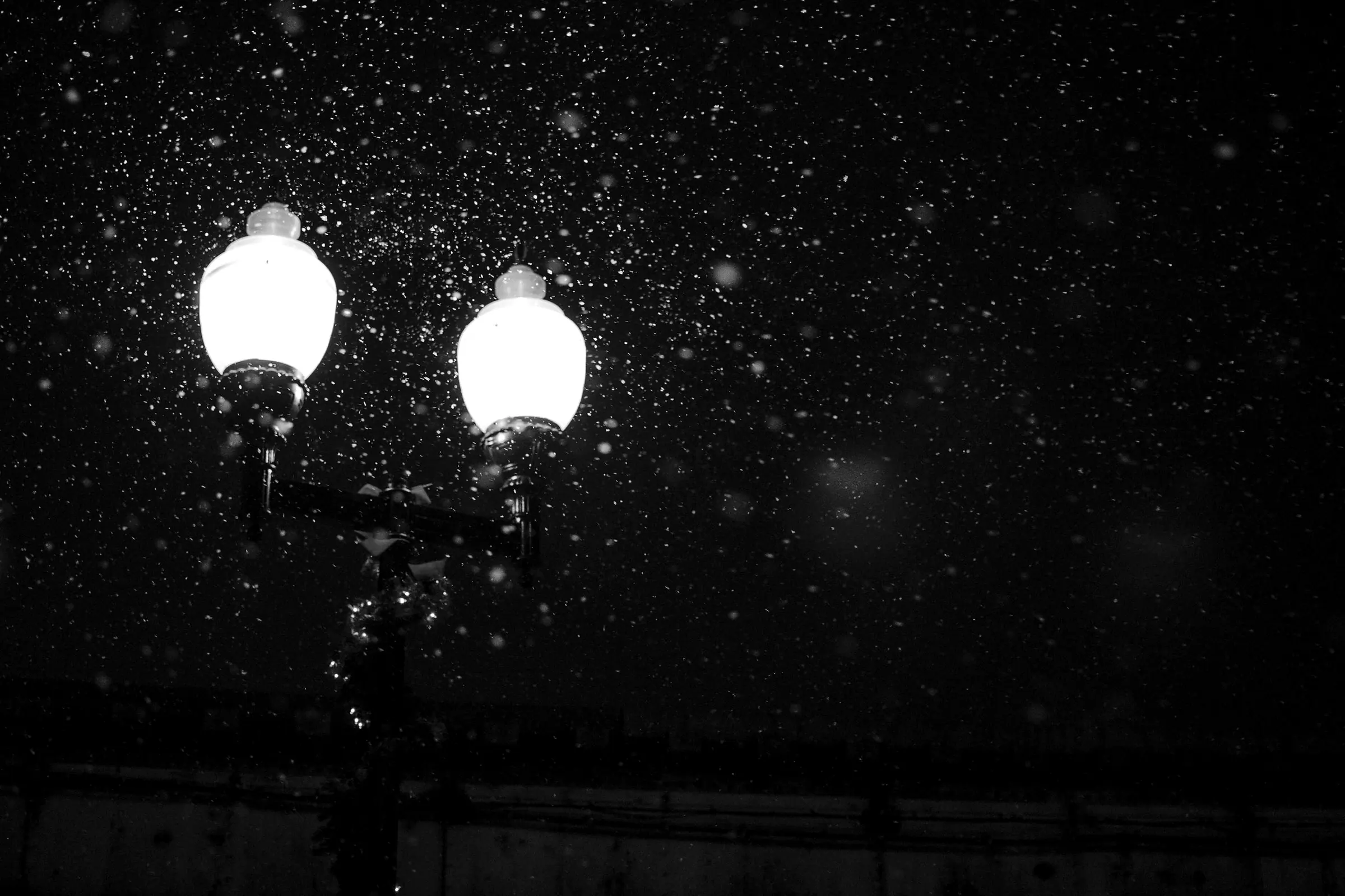 Street lamps in falling snow at night