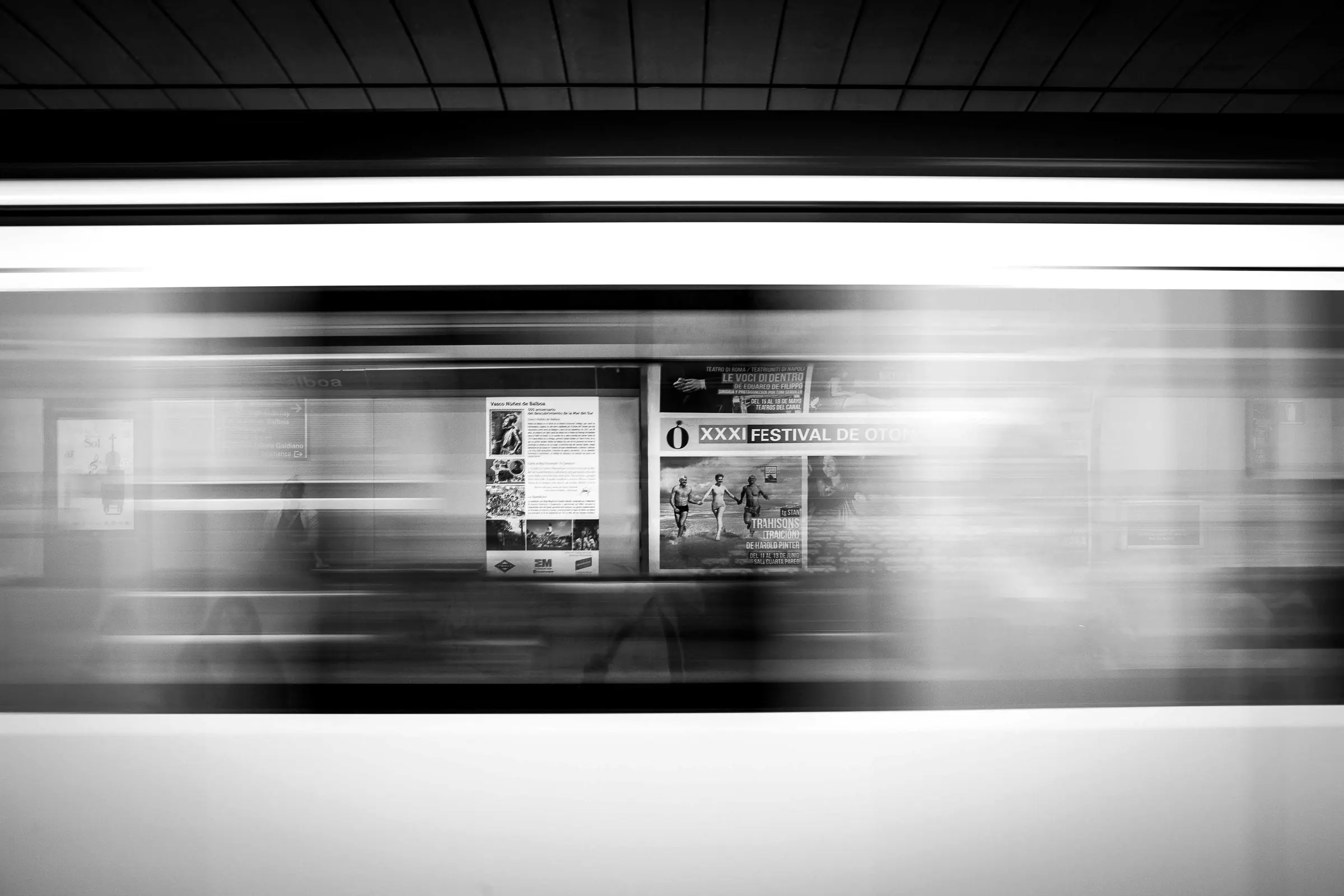 A train streaking past behind a platform advert